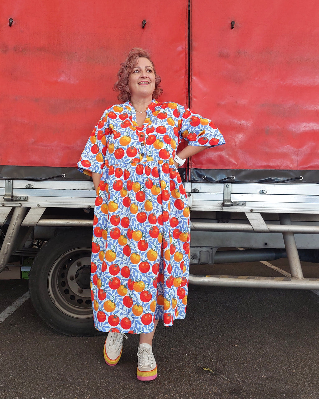 Woman in a colorful dress standing next to a red truck